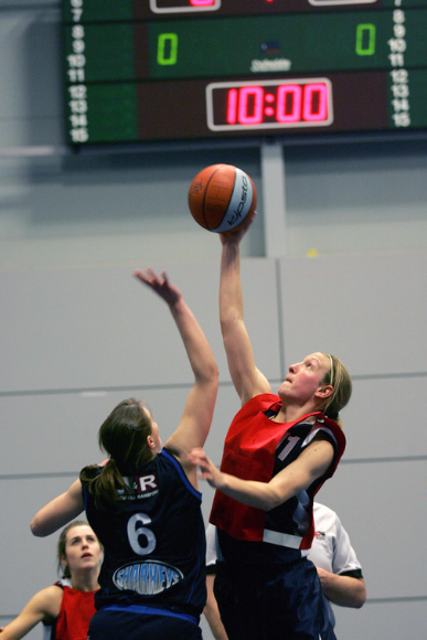 Female student trying to score a point in Netball whilst being blocked by member of the other team